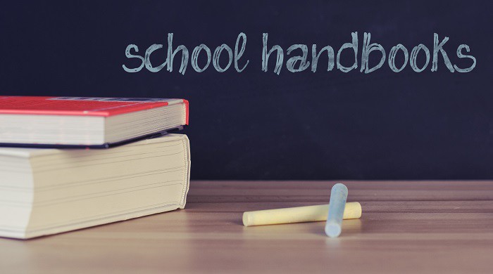 Books next to a chalkboard with the words school handbooks Books next to a chalkboard with the words school handbooks